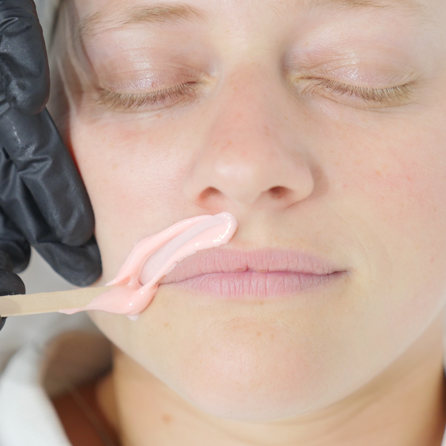 Professional facial waxing treatment using Caronlab Deluxe Strawberry Creme Hard Wax on the upper lip area
