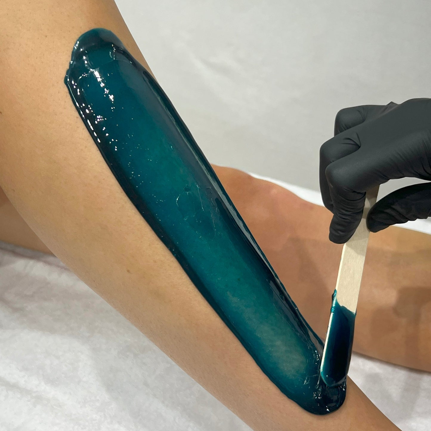 Caronlab Braziliant Film Wax applied thinly to the leg for professional body waxing treatments.