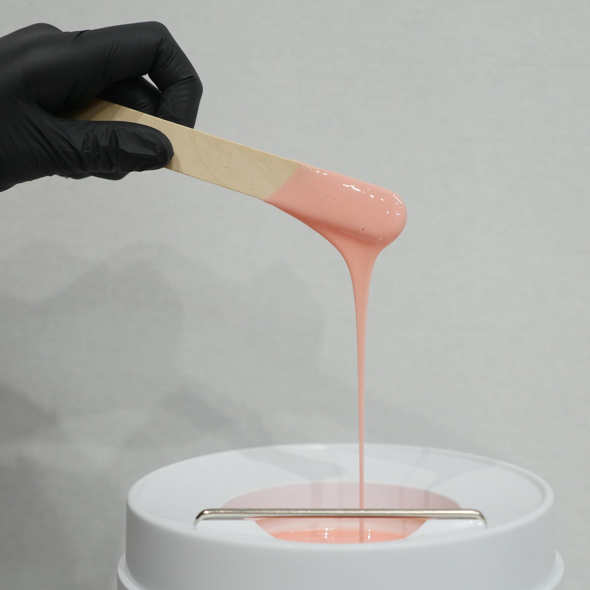 Caronlab Deluxe Strawberry Creme Strip Wax demonstrating smooth creamy consistency for professional waxing services