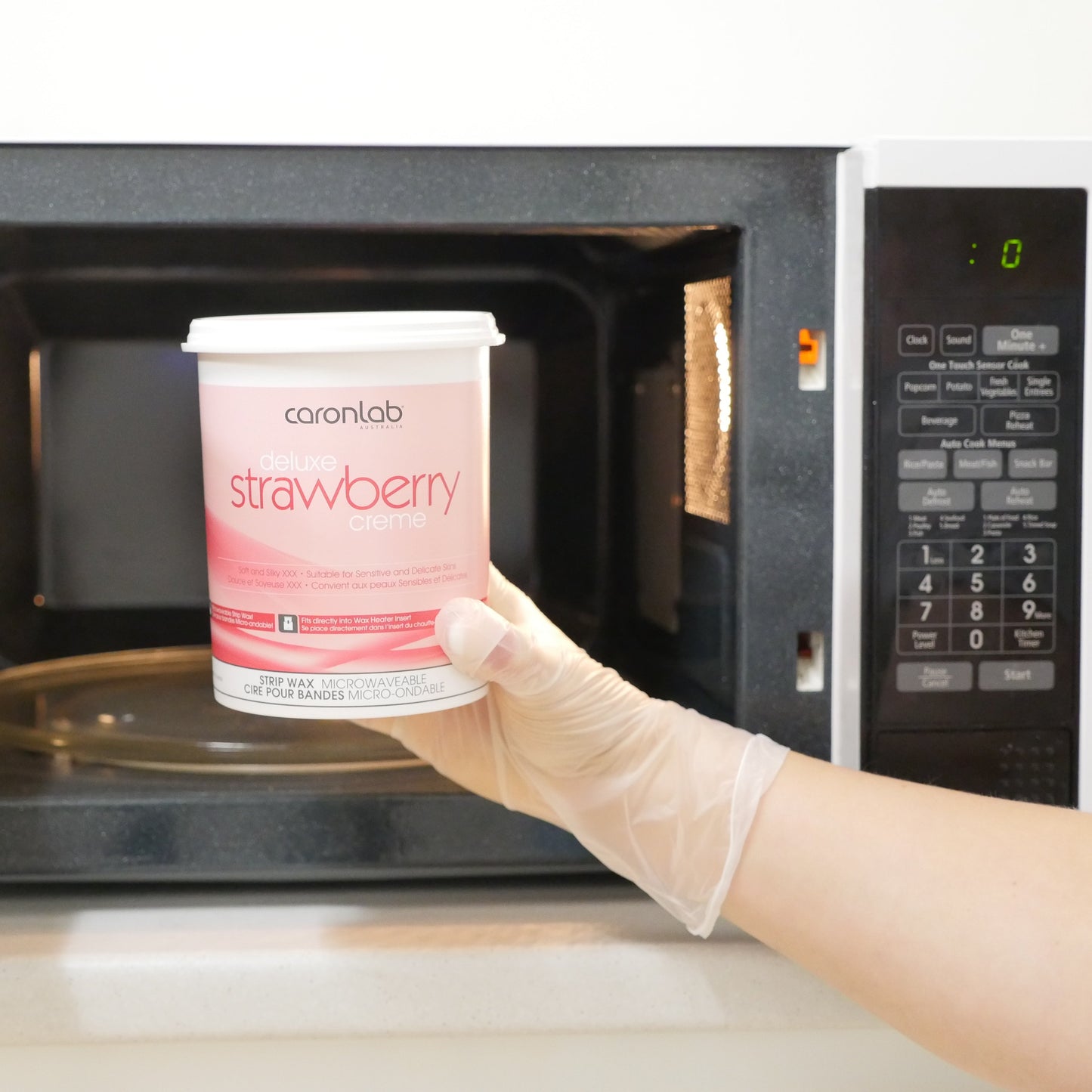 Caronlab Deluxe Strawberry Creme Strip Wax 800ml being heated in a microwave before professional waxing treatment