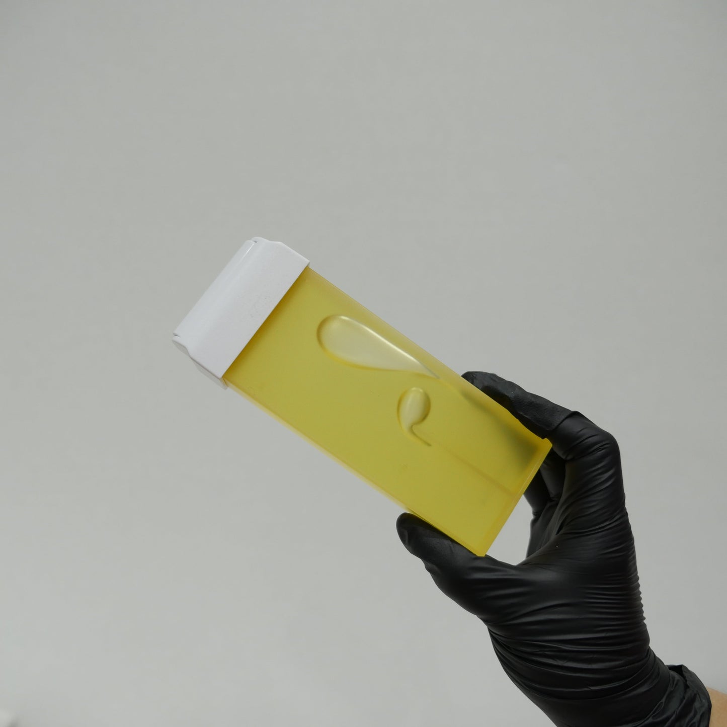 Caronlab Pro HD Strip Wax Cartridge held by a beauty therapist, showcasing the professional roll-on wax cartridge for salon hair removal treatments.