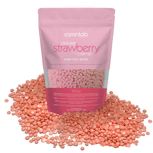 Pink packaging of Caronlab strawberry creme hard wax beads with wax beads spilling out on a white background.