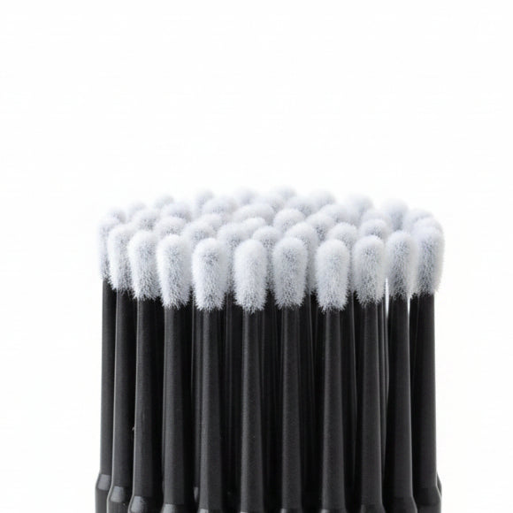 A close-up of a pack of black-handled cotton swab applicators in clear plastic packaging, showing the white cotton tips and dark handles.