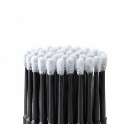 A close-up of a pack of black-handled cotton swab applicators in clear plastic packaging, showing the white cotton tips and dark handles.