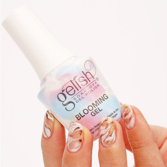 Gelish Blooming Gel bottle held by a hand with decorated nails on a white background