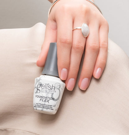 Hand holding a bottle of gelish foundation flex clear and weraing it on nails