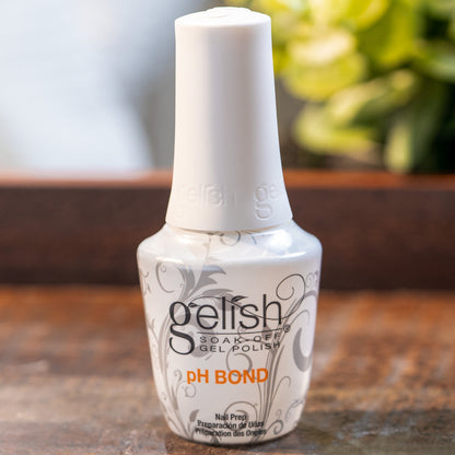 Gelish ph bond bottle on a wooden surface with a blurred plant in the background