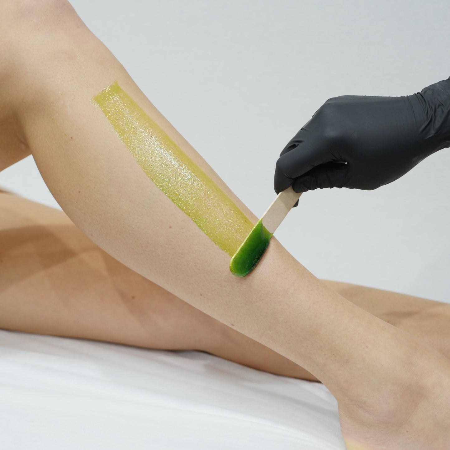 A close-up of a person's leg with a strip of Caronlab's smooth & remove wax being applied.