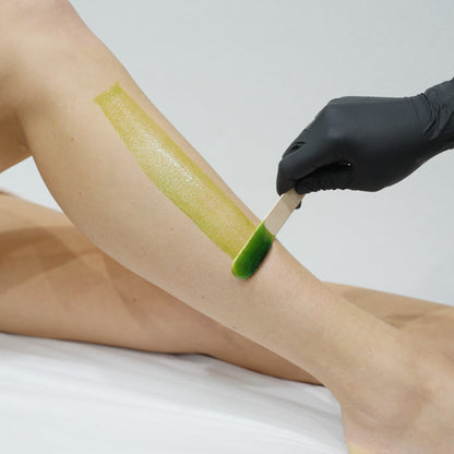 A close-up of a person's leg with a strip of Caronlab's smooth & remove wax being applied.